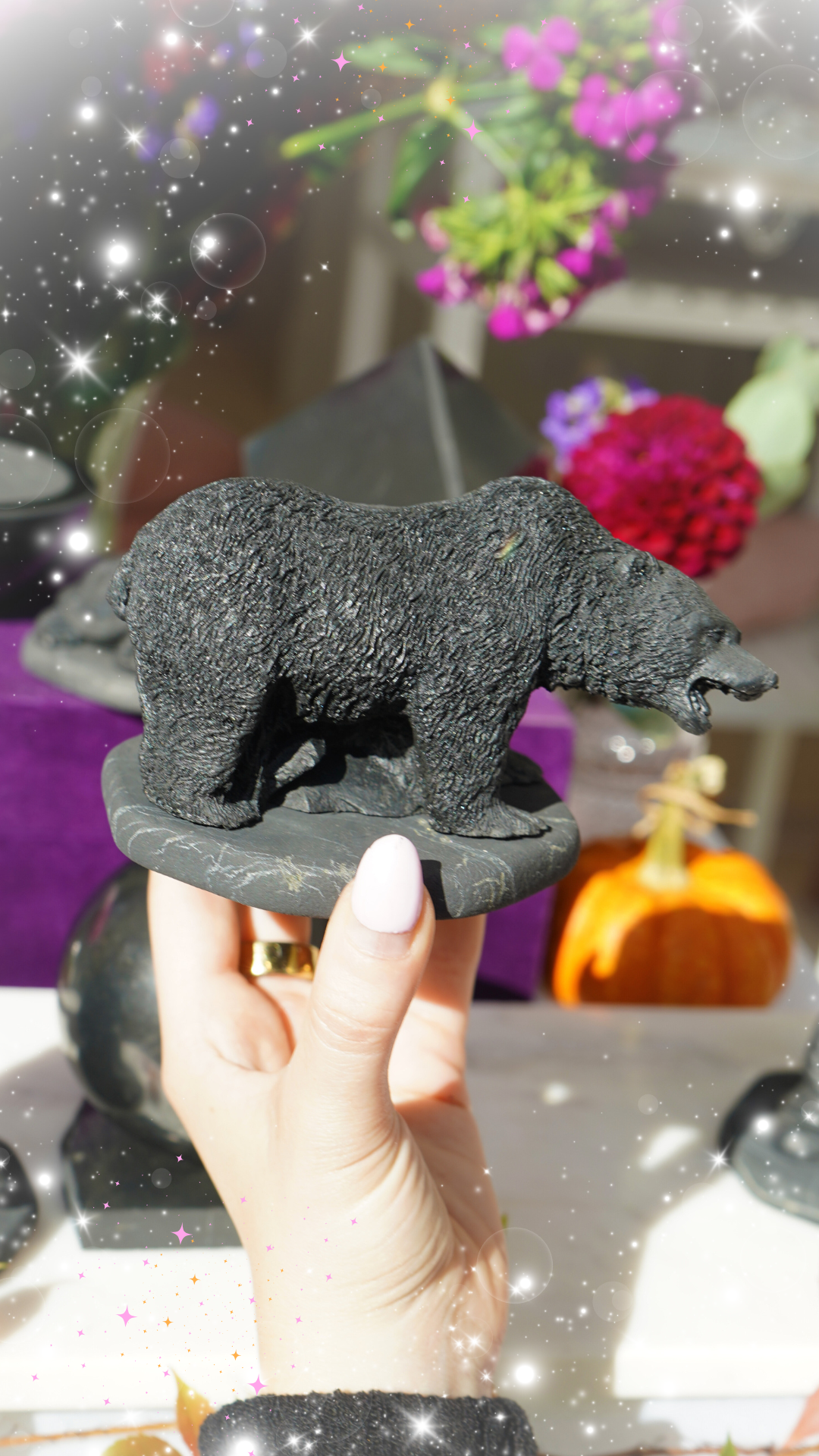 Black bear figurine held by a hand with a colorful blurred background